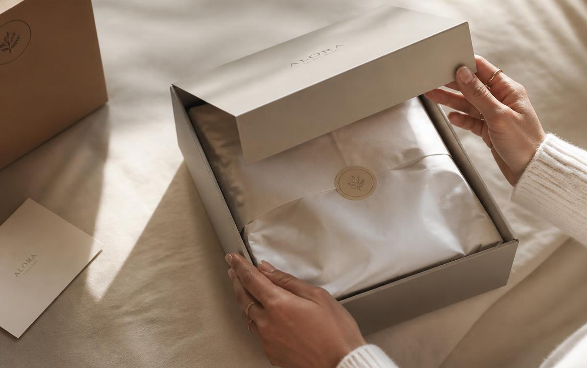 Hands opening a rigid gift box with tissue paper